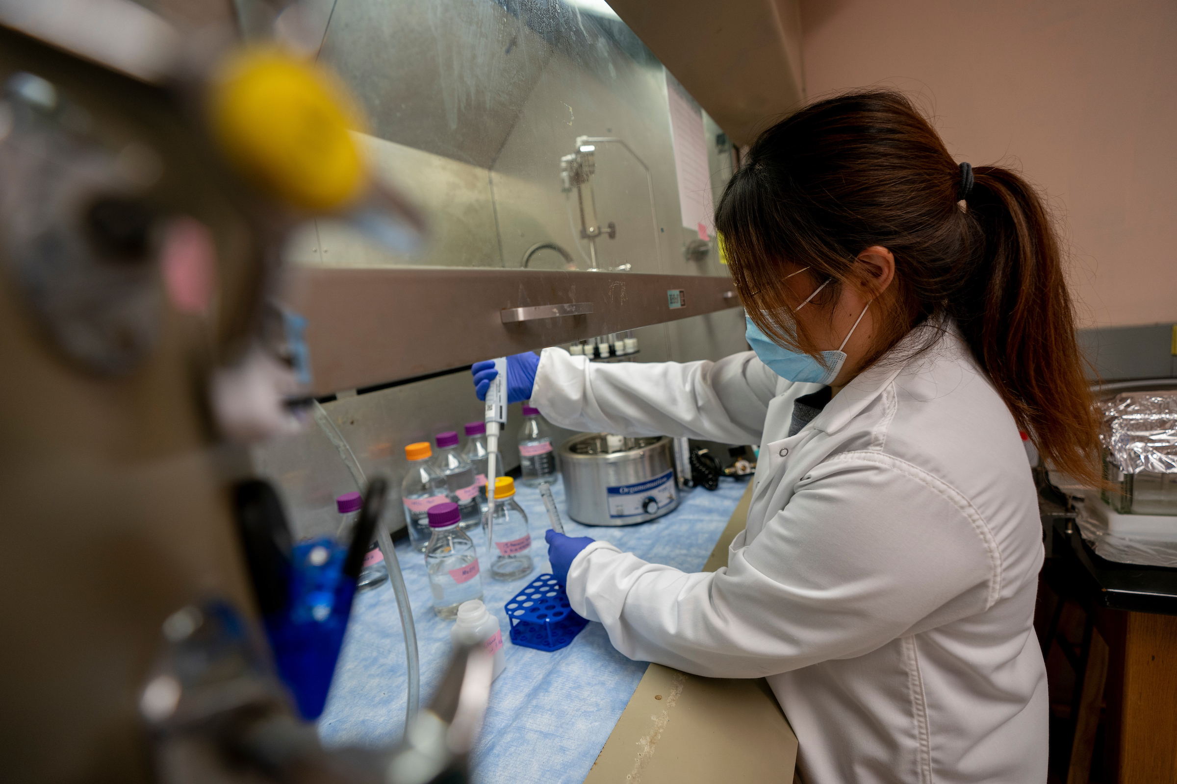 Student wearing a lab coat conducting an experiment
