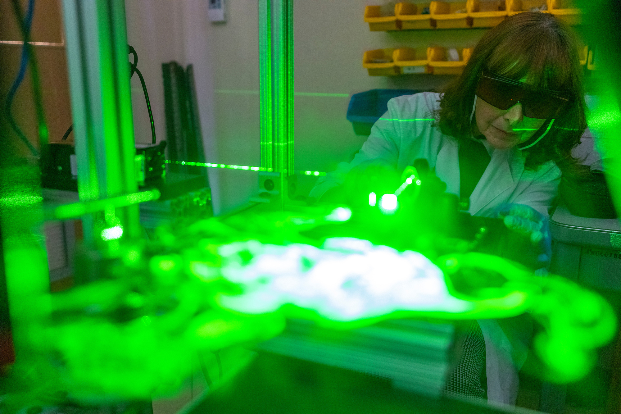 Person wearing protective eyewear and using a machine with lasers.