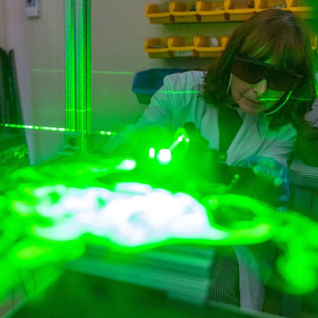 Woman wearing protective eyewear while working with a machine with lasers.