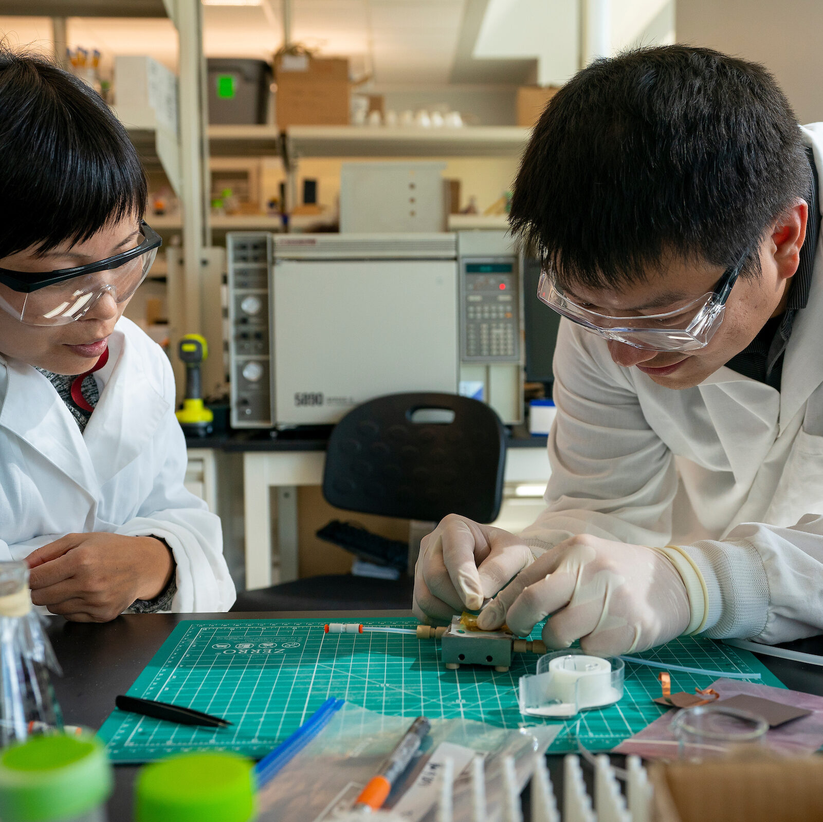 Two students wearing lan safety equipment and working on a project.