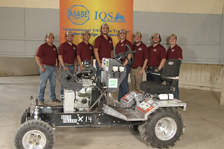 A group of studens representing Aggie Pullers standing behind a tractor they built.