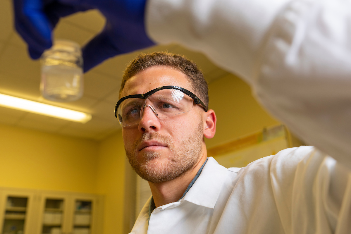Wearing saftey glasses and inspecting a glass vial
