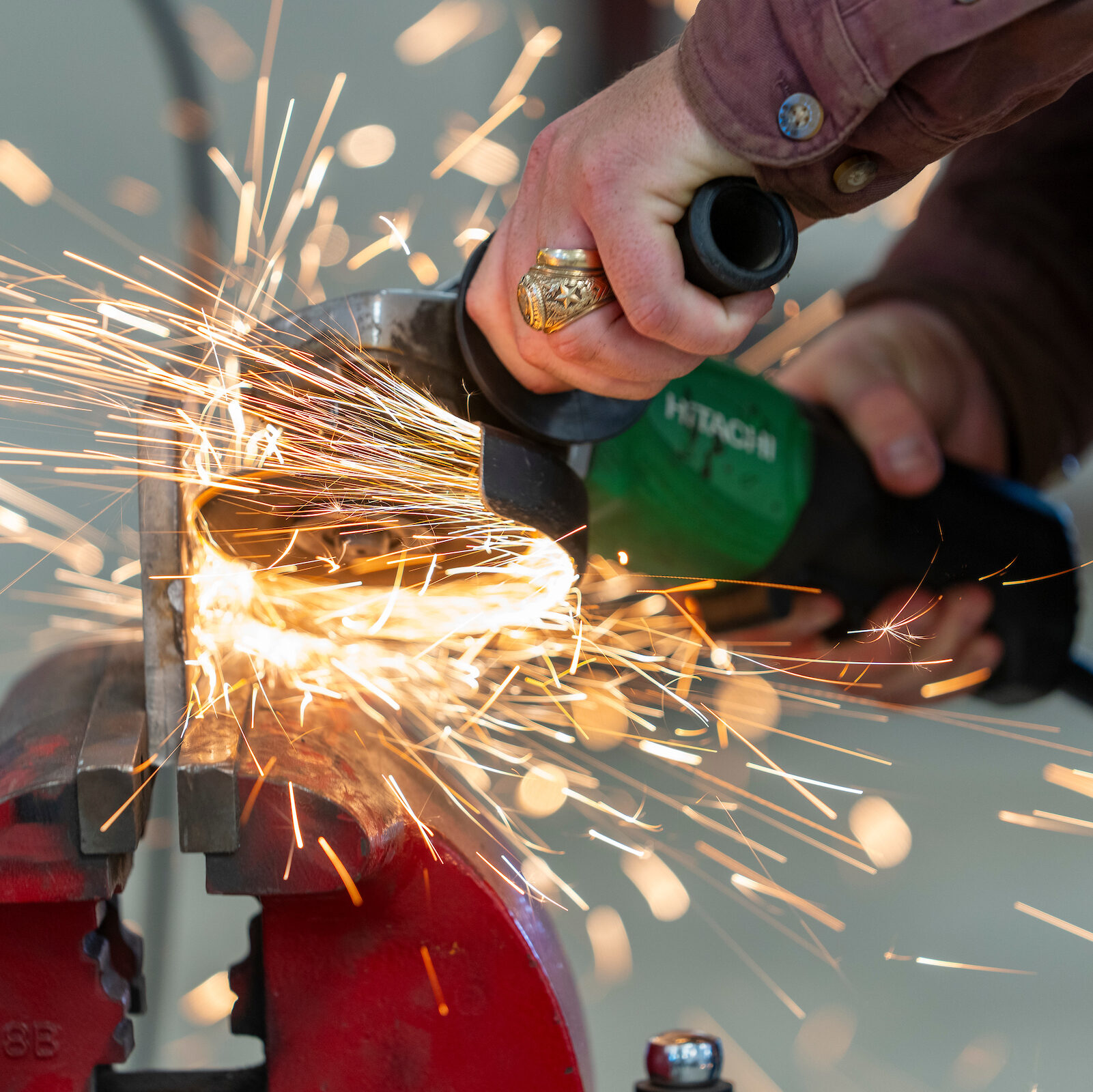 Close up of an Aggie cutting metal wearing his Aggie Ring while sparks fly