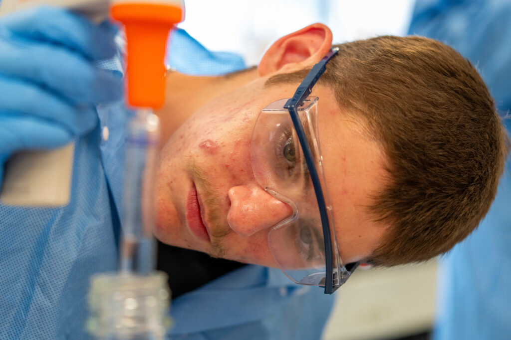 Student wearing safety glasses and measuring a liquid.