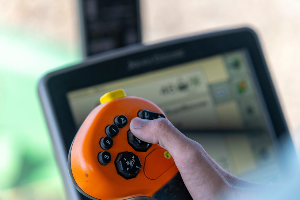 Hand using a remote control on a piece of equipment.